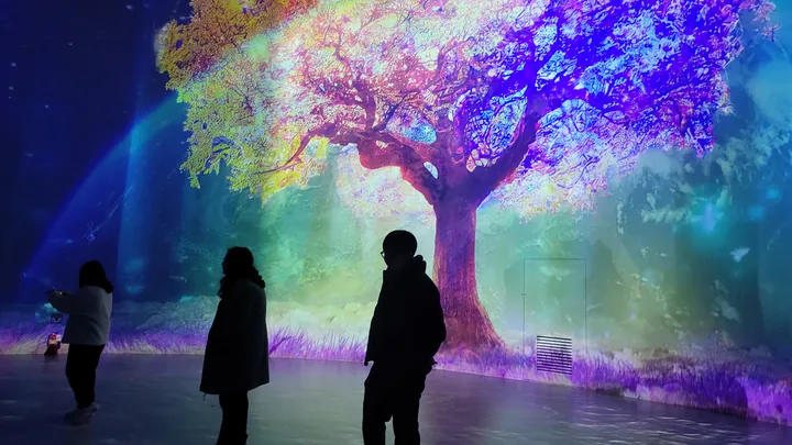 Silhouettes of the team in front of a giant tree of light in a media art hall