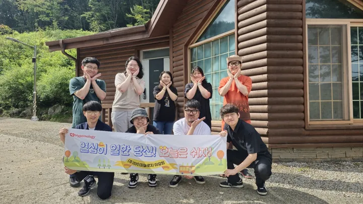 Our team in front of a log cabin, holding the outing banner