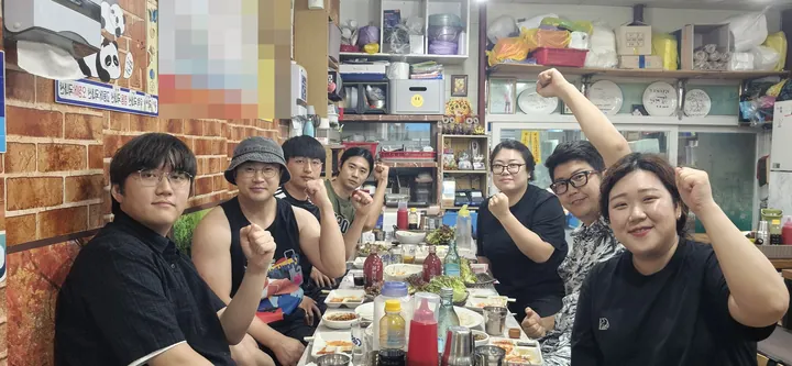 The team at a restaurant, smiling with fists raised together